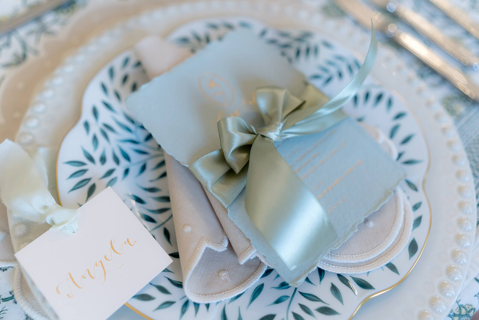 name cardswith gold calligraphy and mint silk ribbon for a spring leafy wedding table style