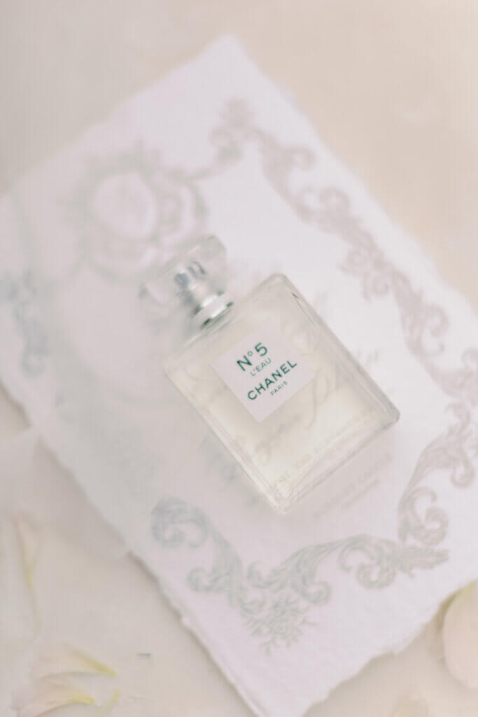 Chanel No. 5 bridal perfume bottle styled on elegant calligraphy stationery with soft petals, luxury wedding flatlay evoking calm and intentionality.