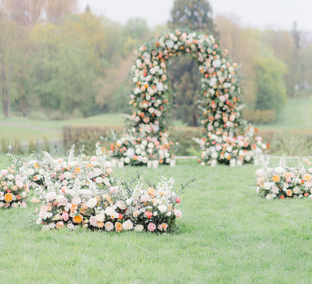 Wedding Ceremony in Castle grounds in Itat with balmy pastel florals in arch on a lawn, and meadows