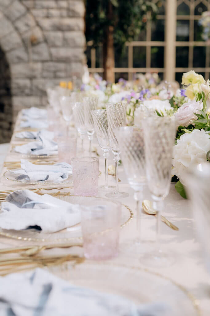 wedding reception light pink crystal glasses, white and gold tableware and light blue napkin