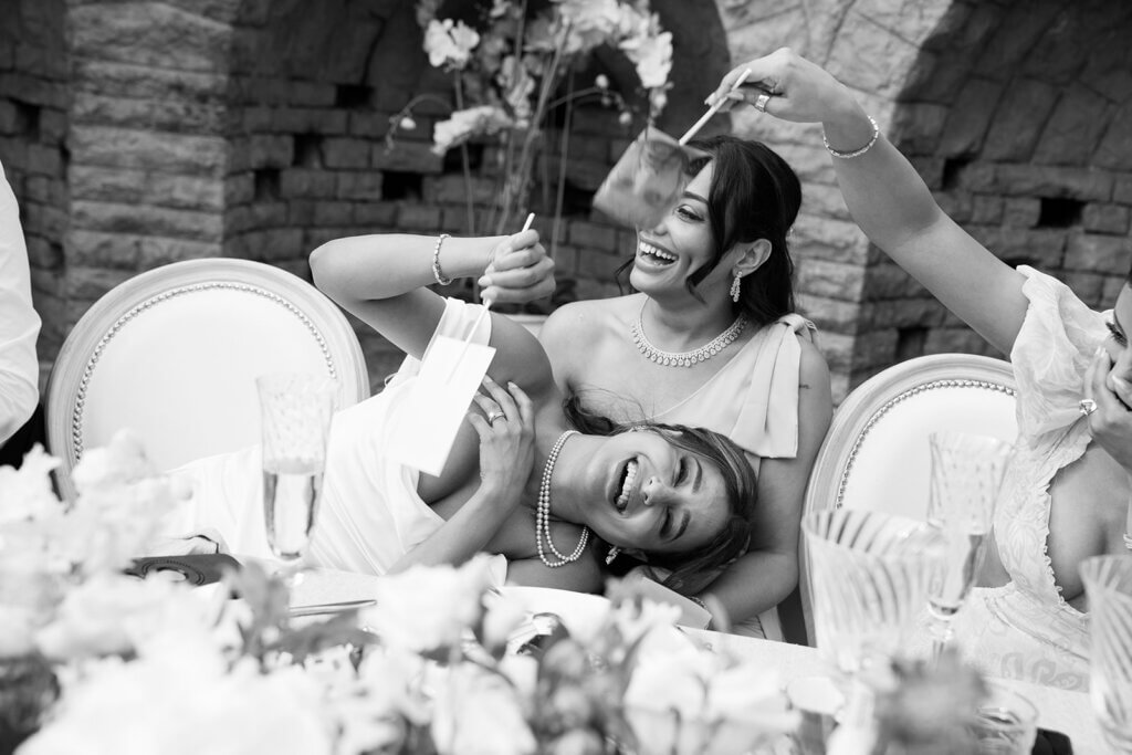 Bride and bridesmaid reacting emotionally to a personal wedding speech during their destination celebration in the Cotswolds