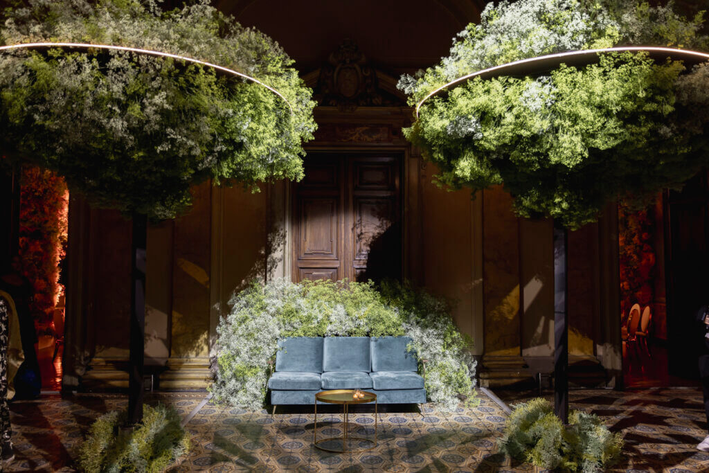dancefloor lounge with trees in corners with halo lights and deep green sofa surrounded by flowers