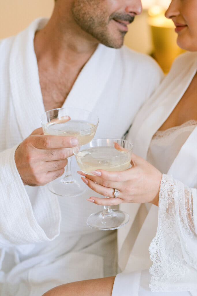 bride and groom sipping champagne from coupes in a rob at the Landmark London hotel.She's wearing a topaz coktail ring