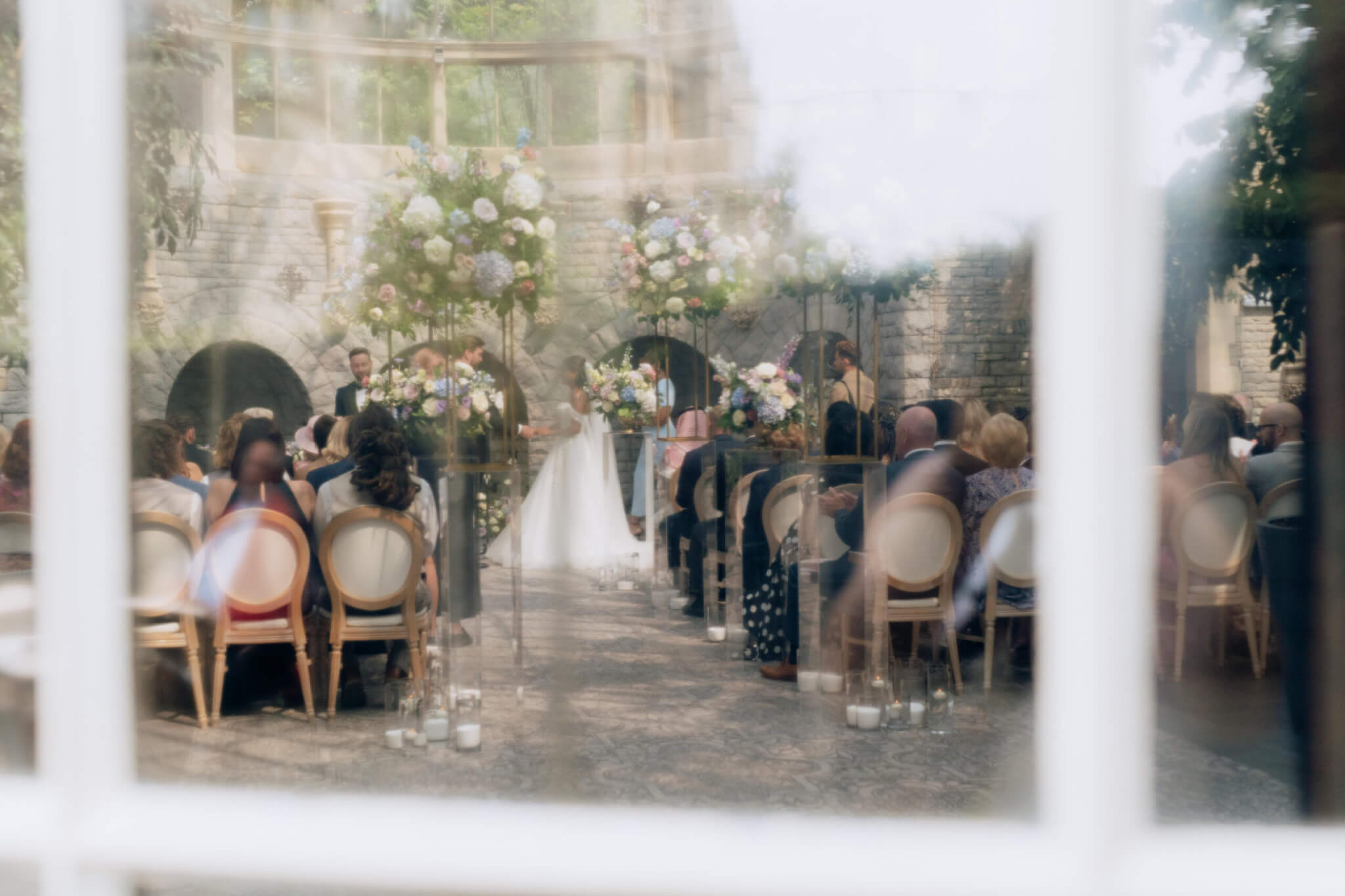 wedding guests sitting in an orangery during a luxurious wedding ceremony in London