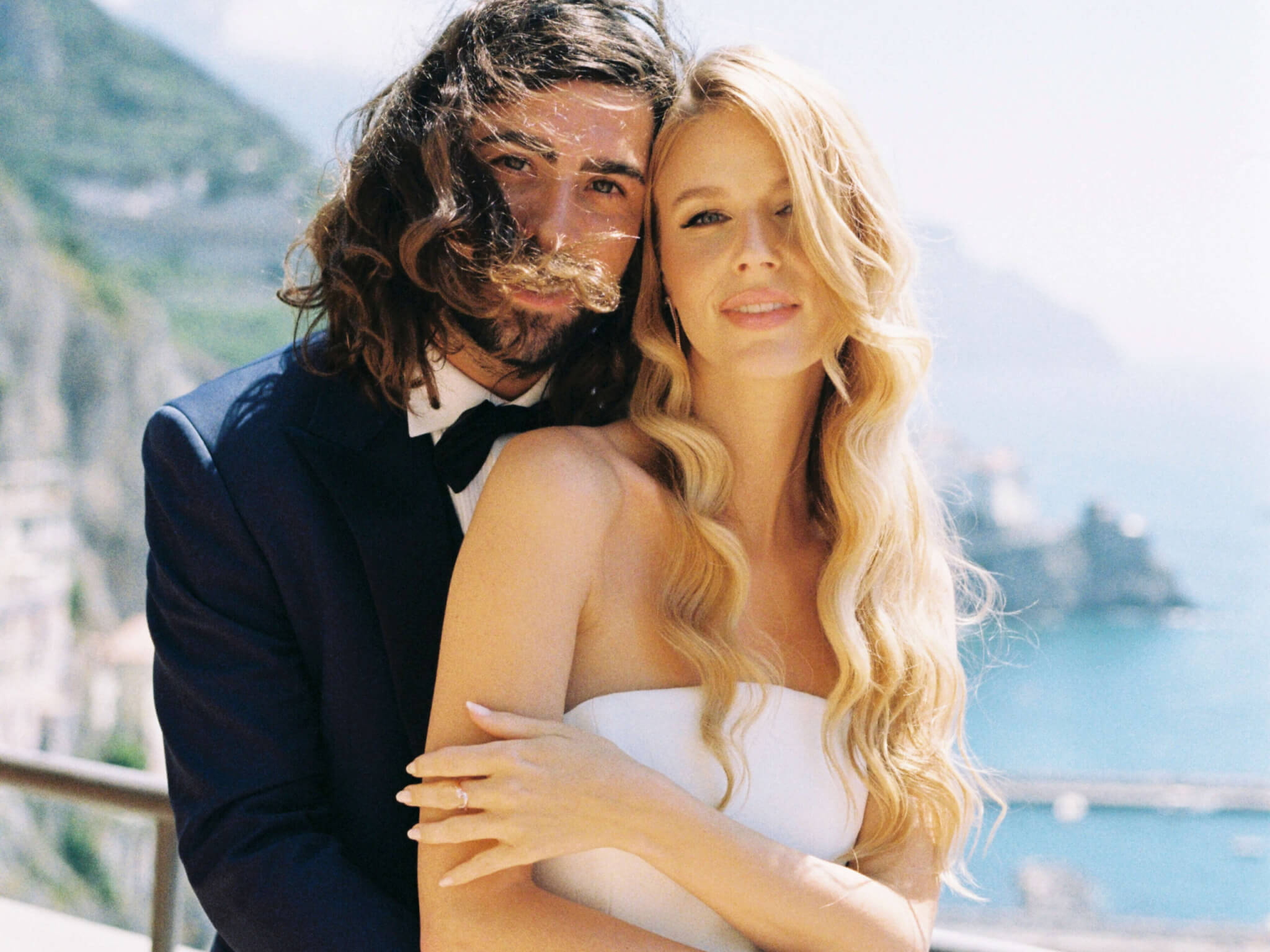  groom hugging bride from behind on sunny terrace with Soft expressions, not posed smiles