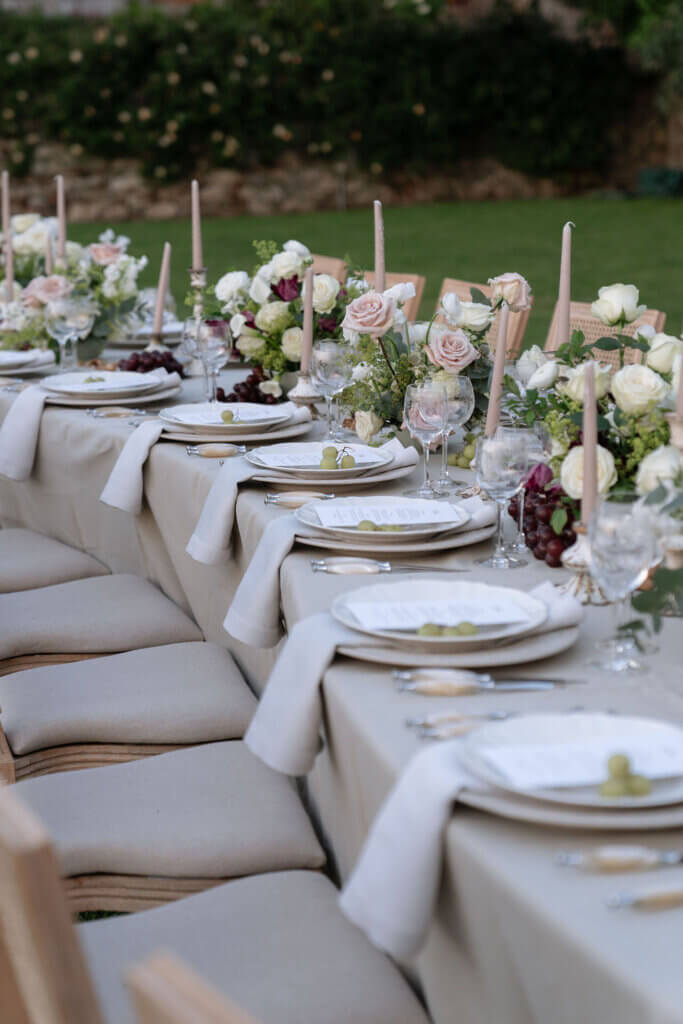 long serpentine luxury wedding reception table in a villa garden with elegant set up, burgundy, taupe and ivory florals and fruits